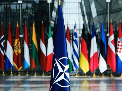 The NATO flag with several other flags behind it.