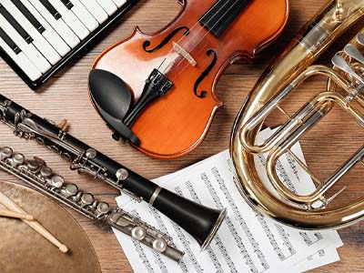 A flute, a violin, and a keyboard, along with other musical instruments on a table.