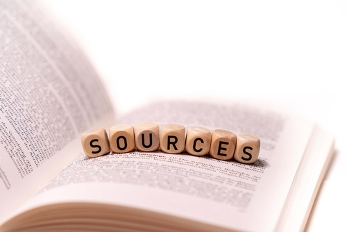 the word SOURCES spelled on an open book with wooden letters, concept picture with white background