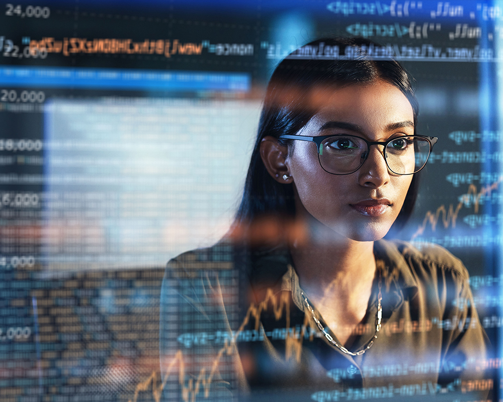 A person with glasses looking at a large screen of code.