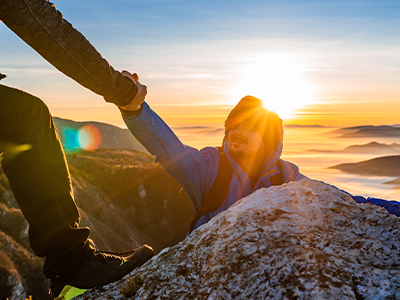 A person being helped up the side of a mountain.