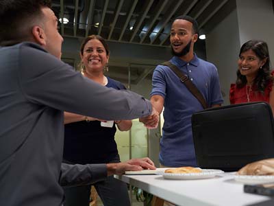 Two people shaking hands while two other people look on and smile.