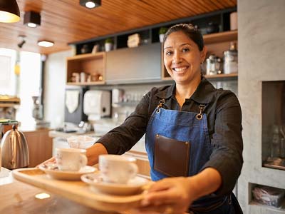 A person in an apron serving coffee.