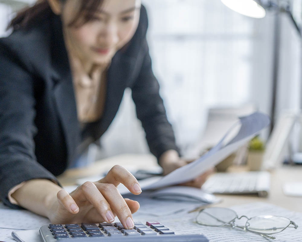 A person using a calculator and holding papers.