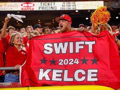 A person cheering and holding a sign that says, "Swift Kelce 2024."