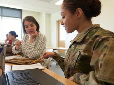 A person in uniform pointing to notes while another person looks on.