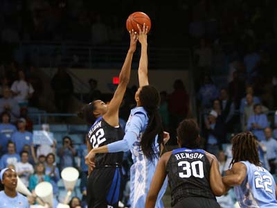 Two basketball players jumping up for a jump ball.