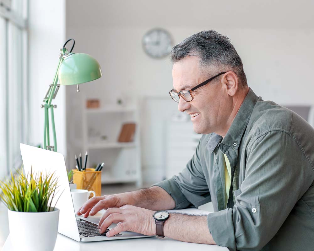 A person typing on a laptop and smiling.