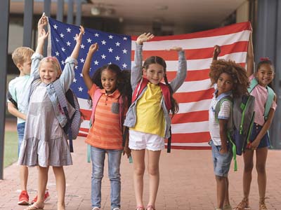 Children with their hands up holding an American flag.