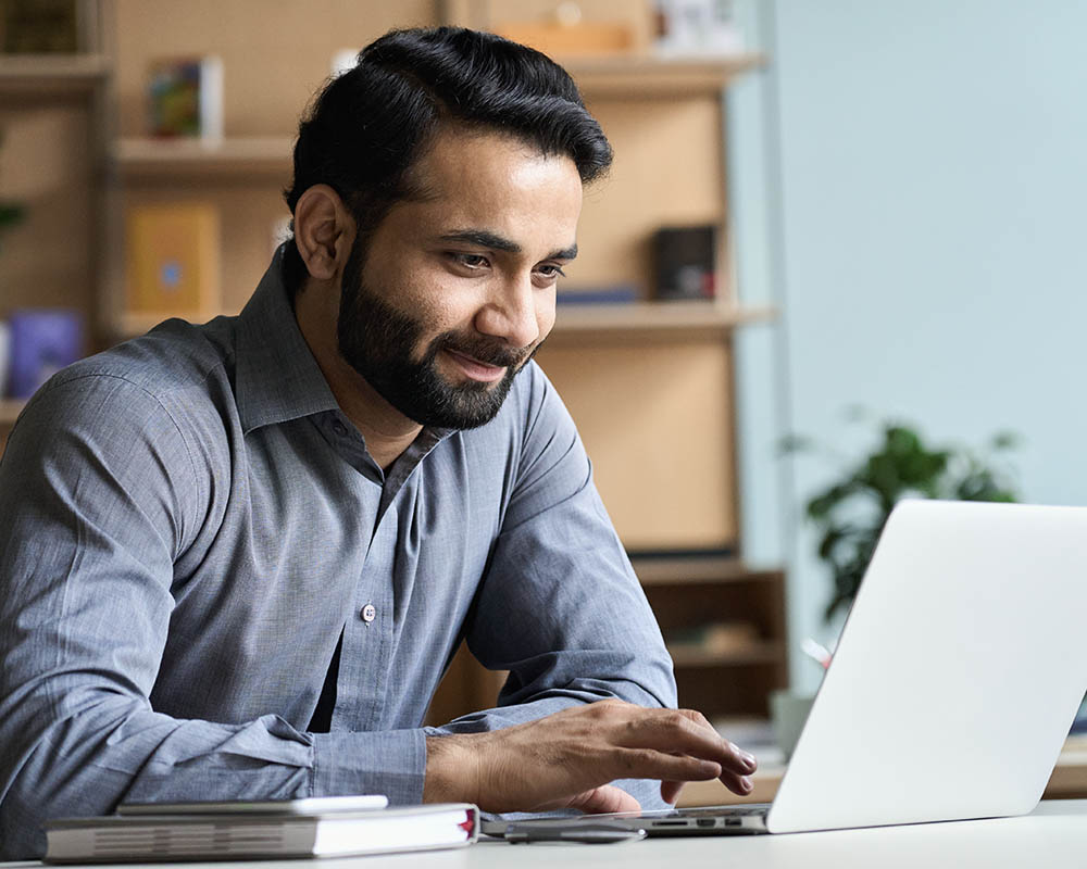 A person typing on a laptop and smiling.