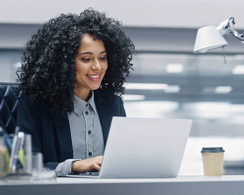 A person typing on a laptop and smiling.