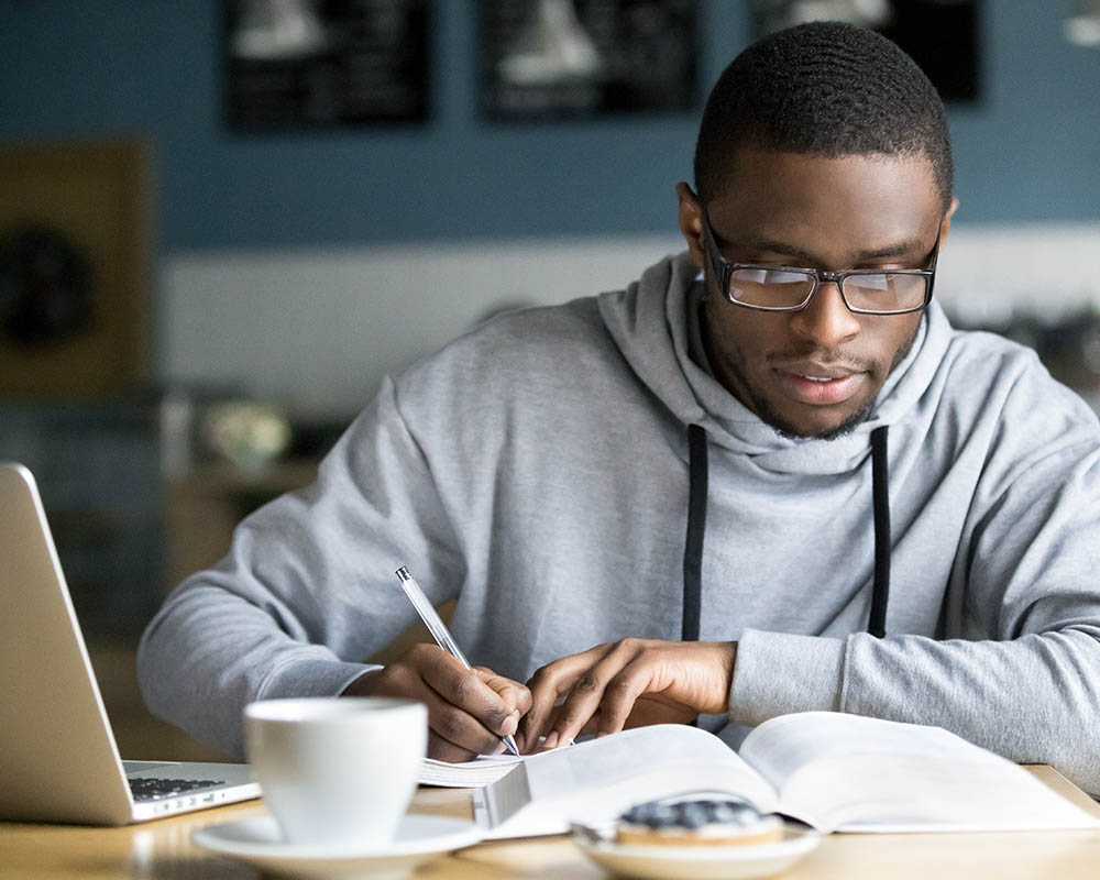 A person reading a book and taking notes.