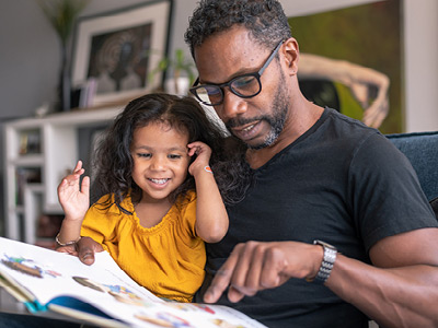 An adult and a child looking at a children's book.