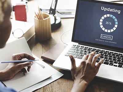 A person working on a laptop whose screen says, "Updating."