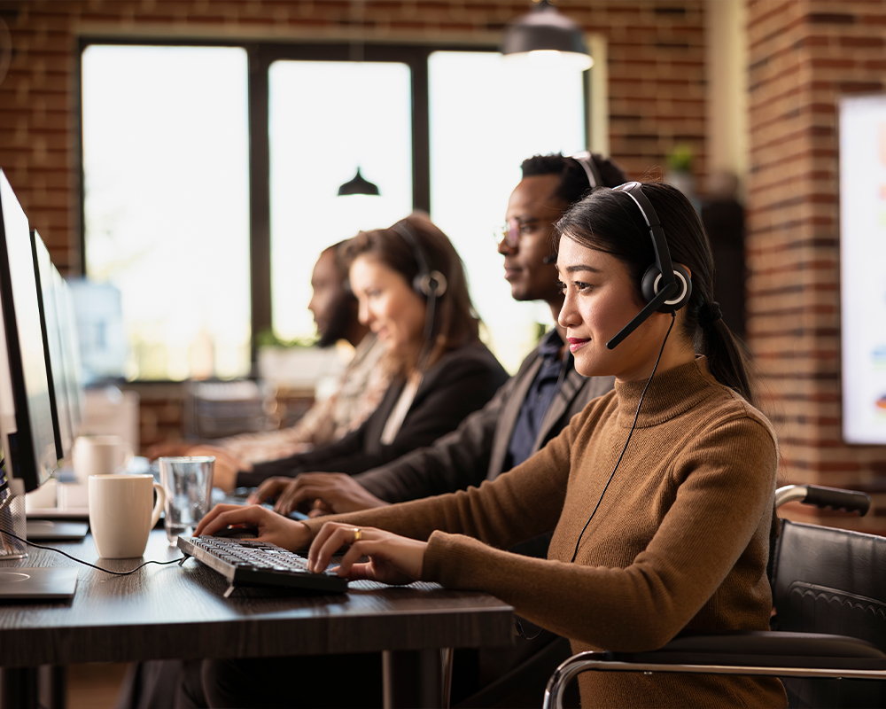 Four people with headphones sitting and working on computers.