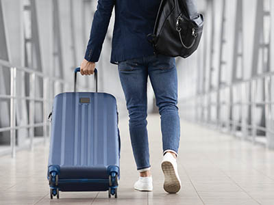 A person walking and wheeling a carry-on piece of luggage.