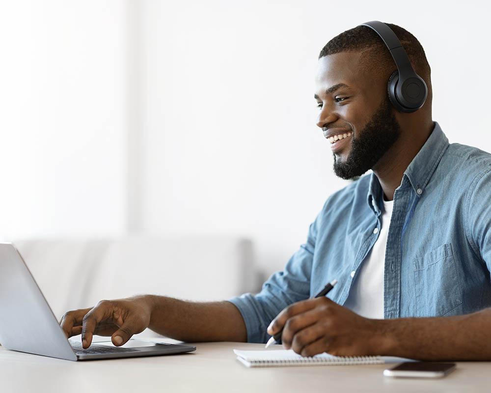 A person wearing headphones using a laptop.