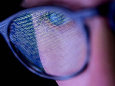 A person wearing eyeglasses reflecting lines of code.