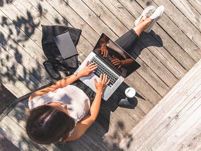 A bird's eye view of a person sitting outside with a laptop on their lap.