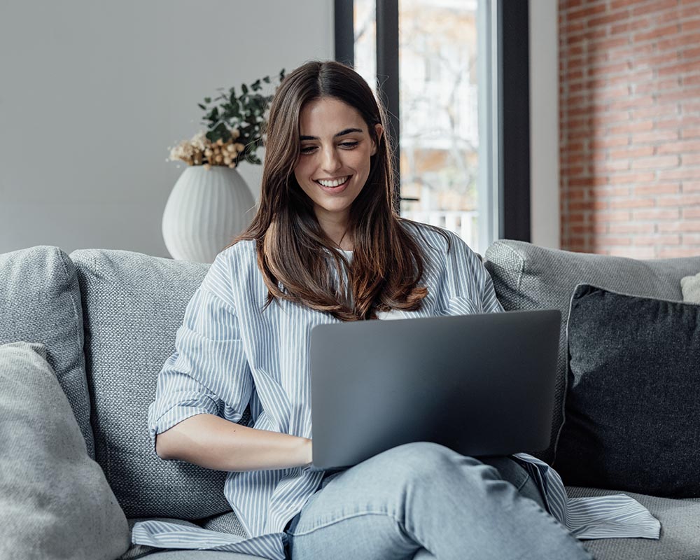 A person smiling and working on a laptop.