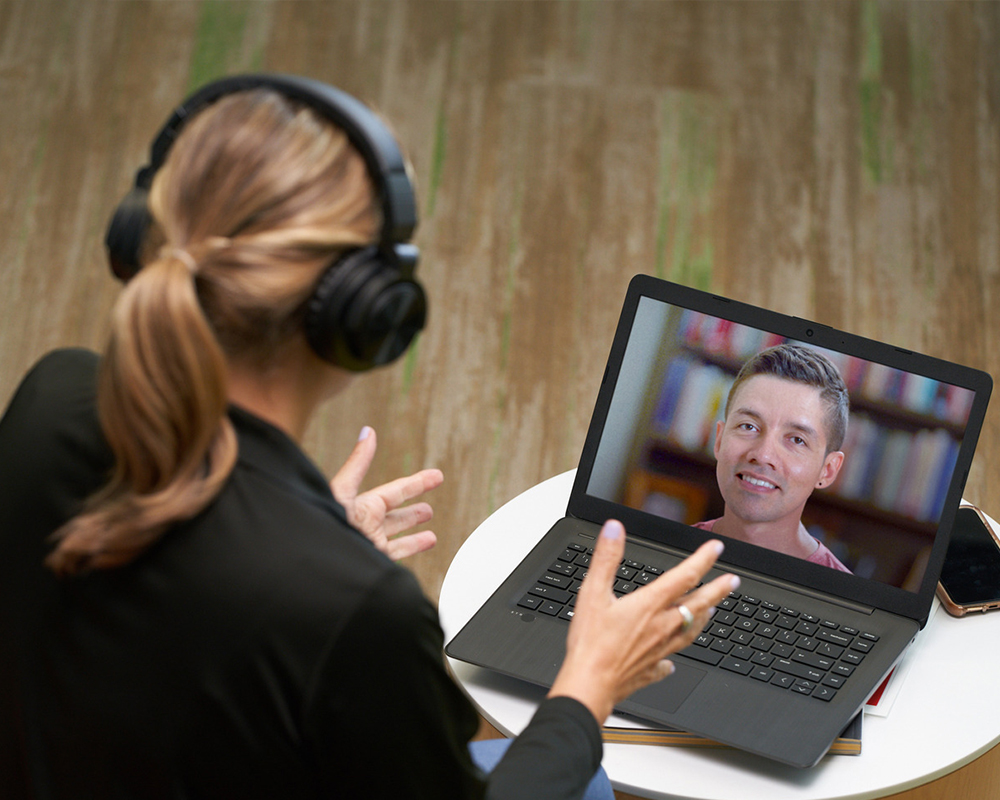 A person with headphones on a video chat with another person.