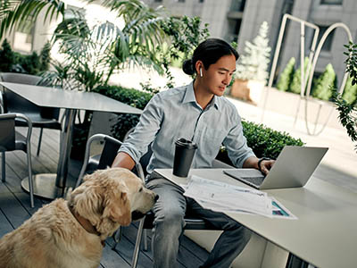 A person using a laptop at an outside table.