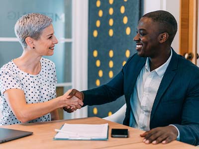 Two people shaking hands and smiling.