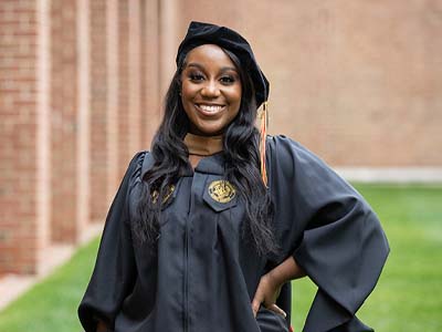 A person in graduation regalia smiling at the camera.