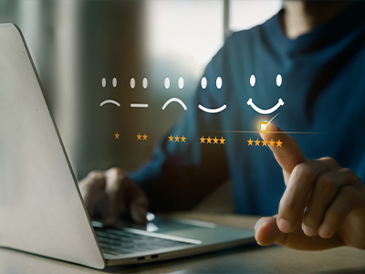 A person using a laptop and selecting a five-star review.