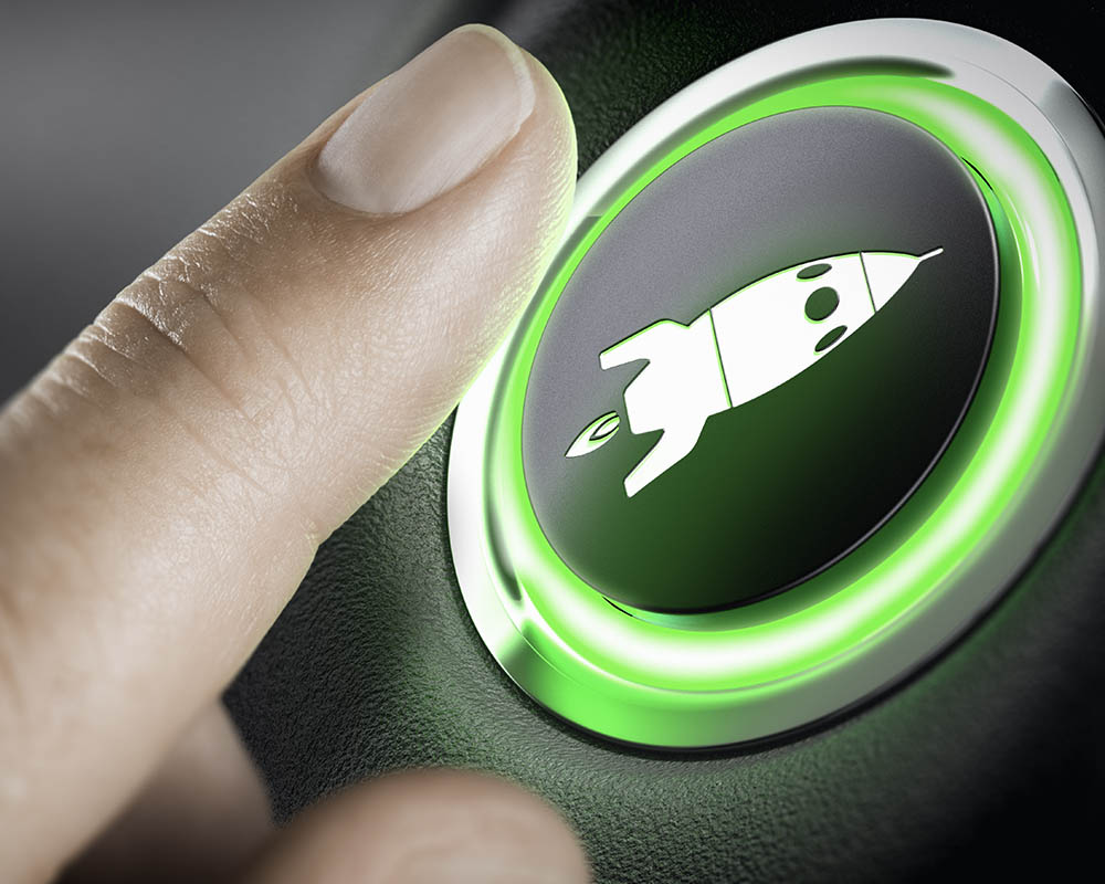 A person's finger pressing a button with an image of a rocket ship on it.