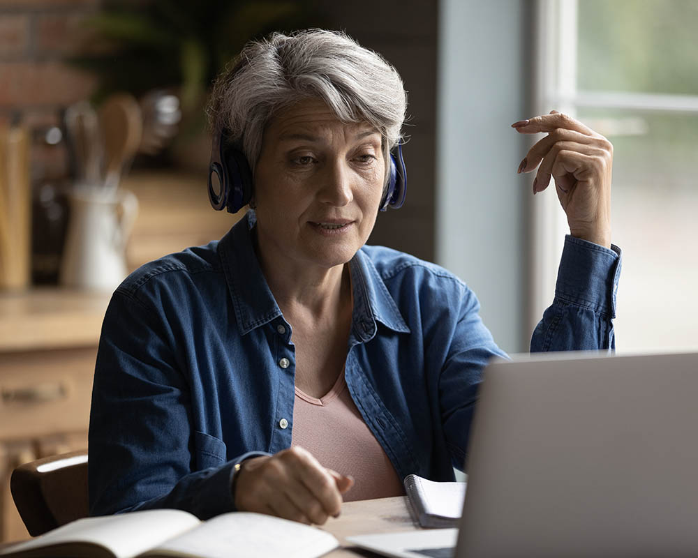 A person wearing headphones and looking at a laptop.