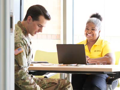 Two people sitting at a table; one is in a military uniform.