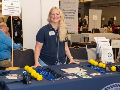 A person standing behind a table with giveaways and information.
