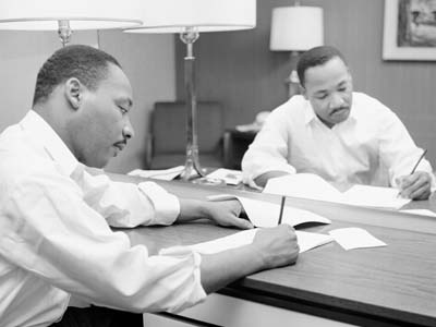 Black and white photo of Martin Luther King, Jr. writing at a desk.