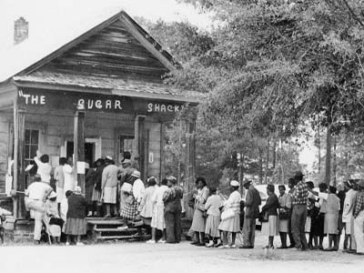 Black and white photo of people lined up to vote outside the Sugar Shack in Peachtree, Alabama.