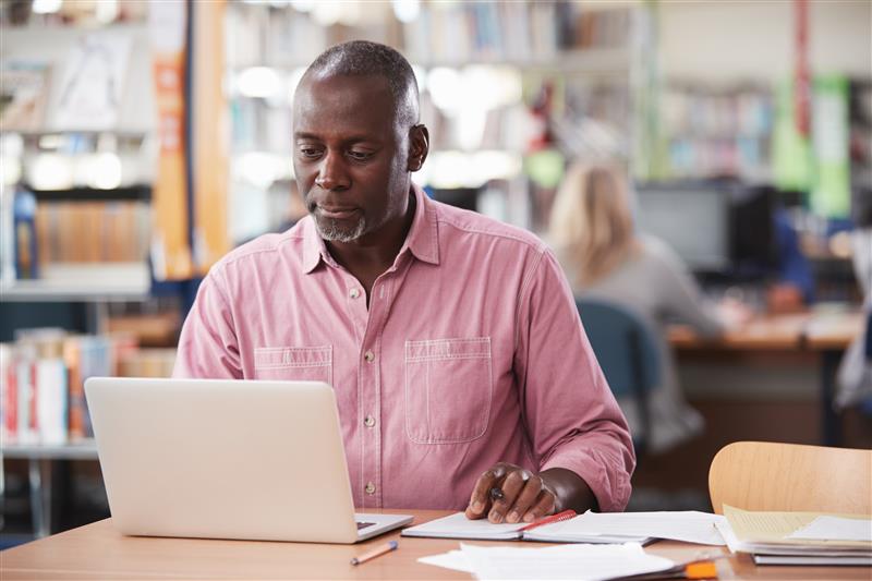 A person using a laptop and taking notes.