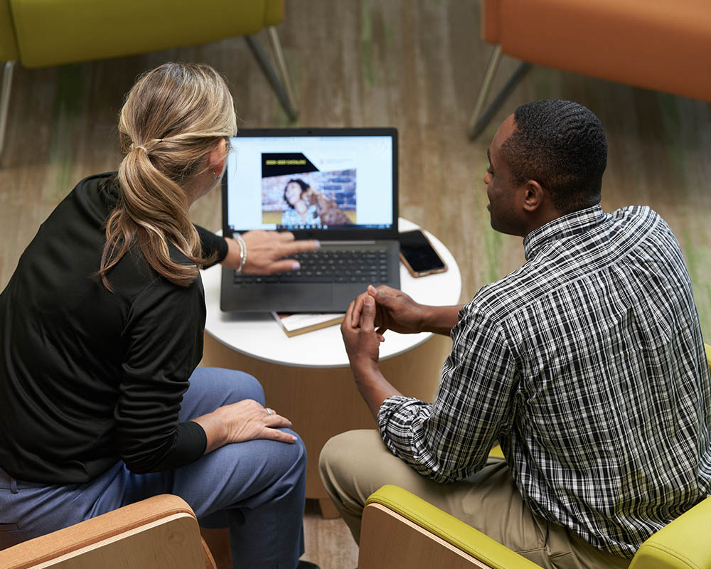 Two people looking at a laptop.