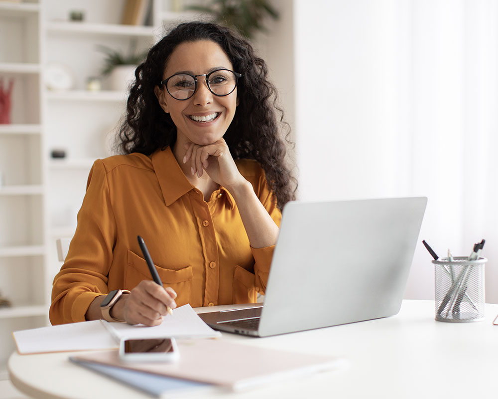 A person smiling while writing in a notebook.