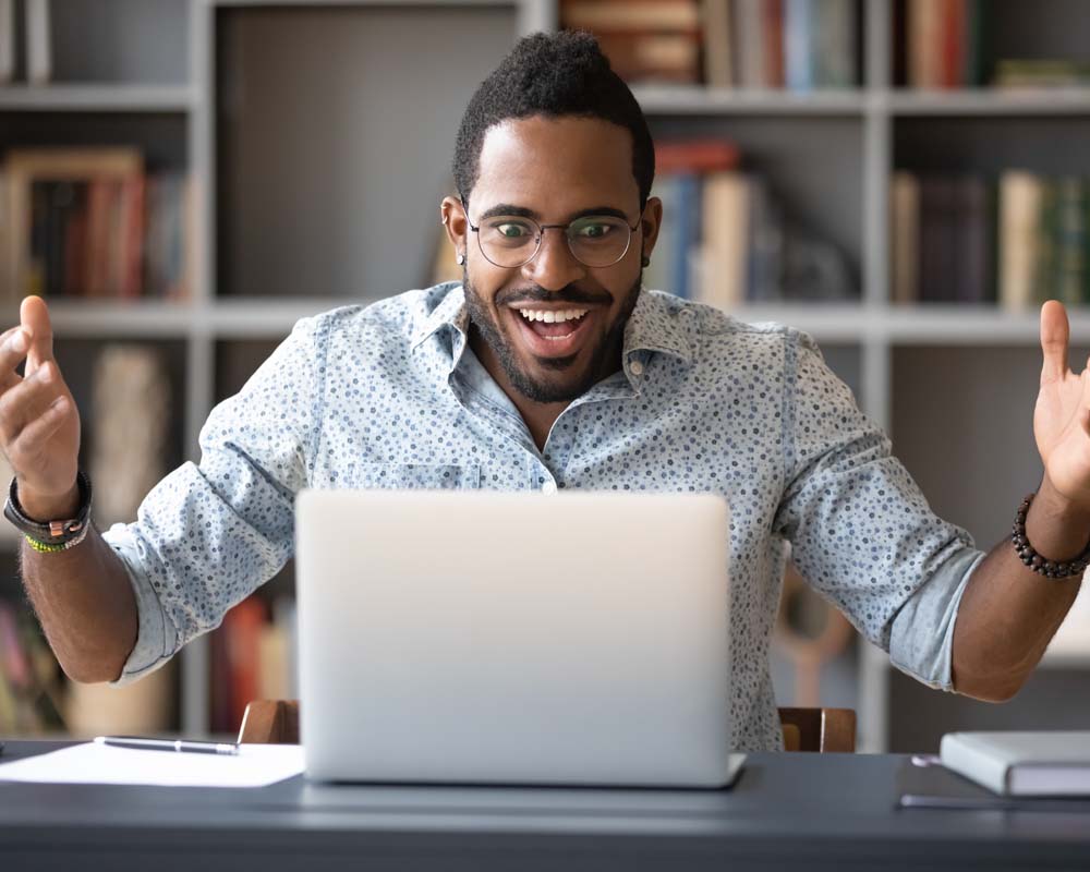 A person looking at a laptop screen and smiling widely.