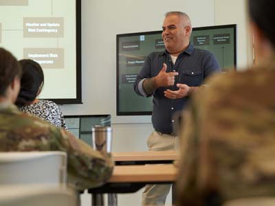 A person giving a presentation to people wearing military uniforms.