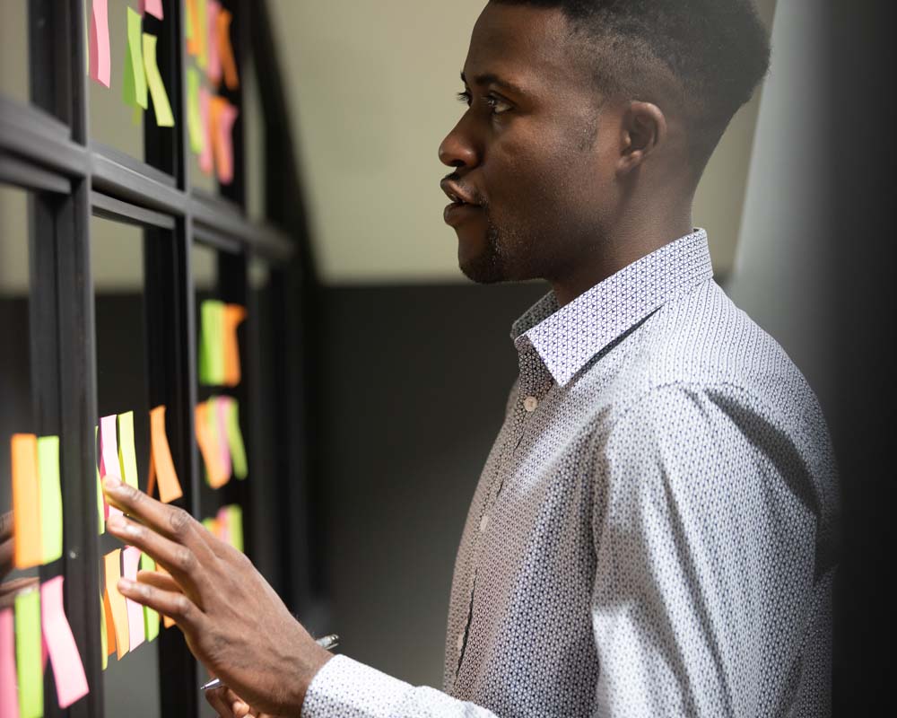 A person looking at post-it notes on a wall.