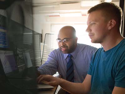 Two people working on a computer together.