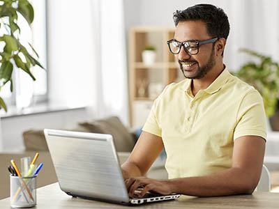 A person typing on a laptop and smiling.