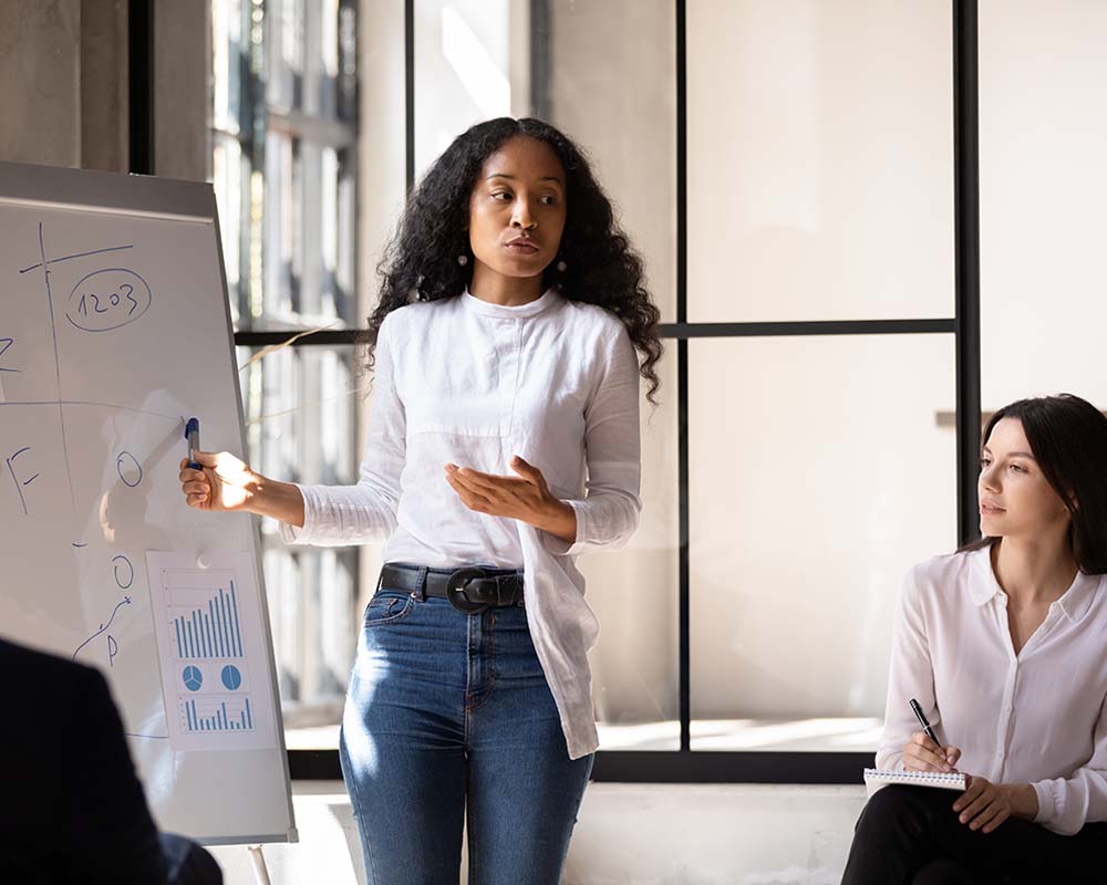 A person standing and presenting data on a white board.