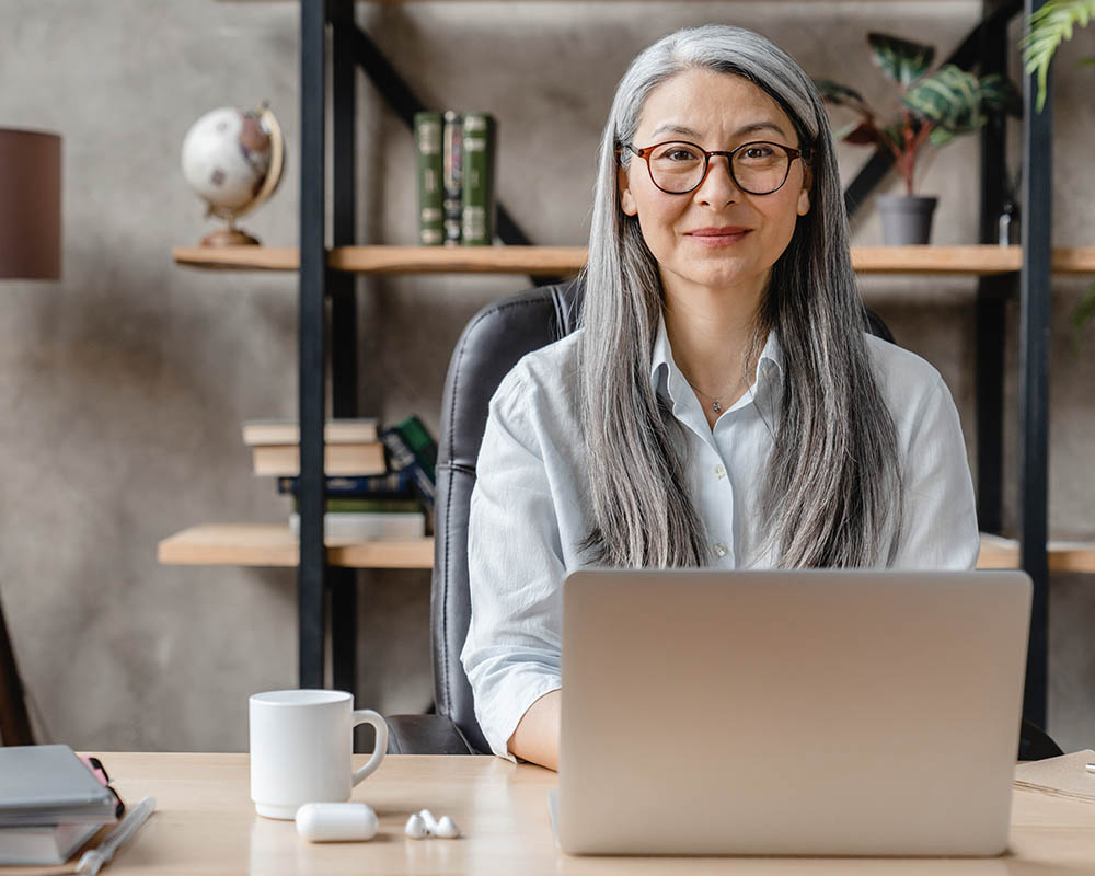 A person working on a laptop, subtly smiling.