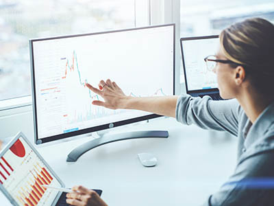 A person pointing to a chart on a computer screen.