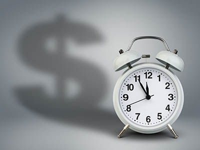 A small clock whose shadow is oddly the shape of a dollar sign.