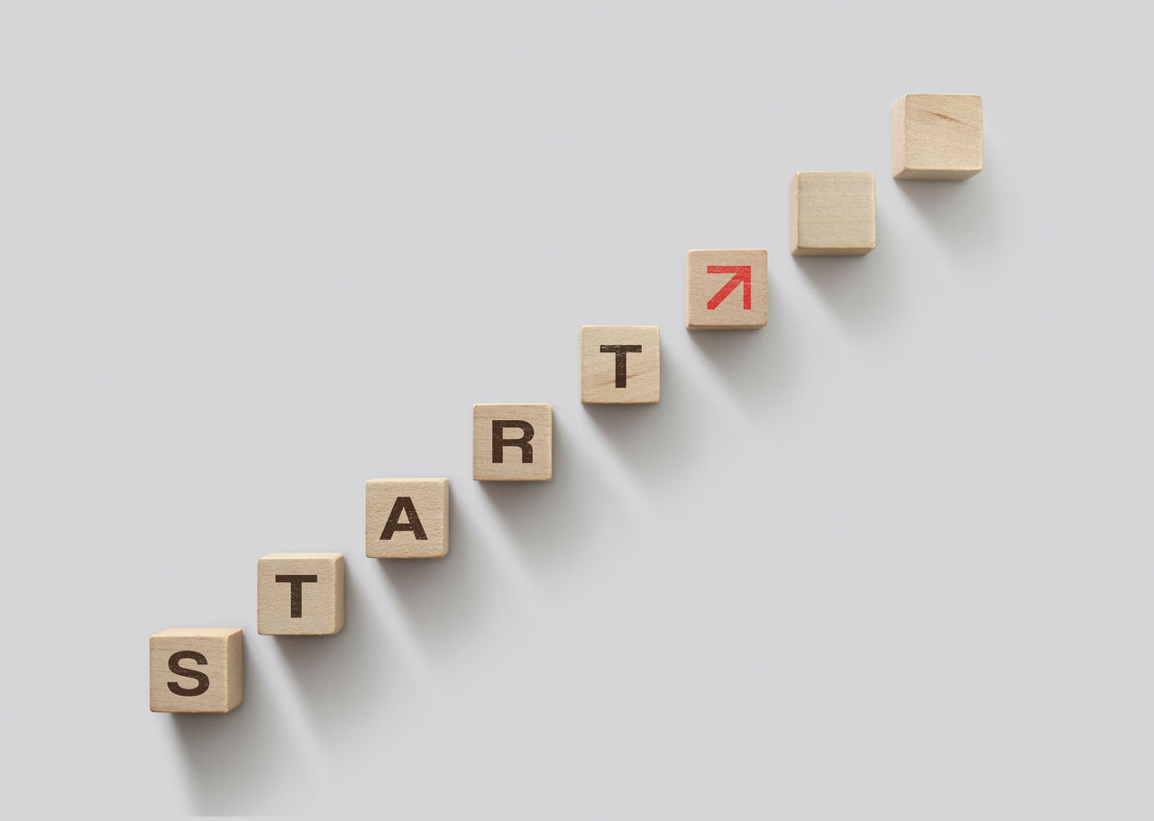 The word 'start' spelled out using wooden blocks with red arrow pointing upwards