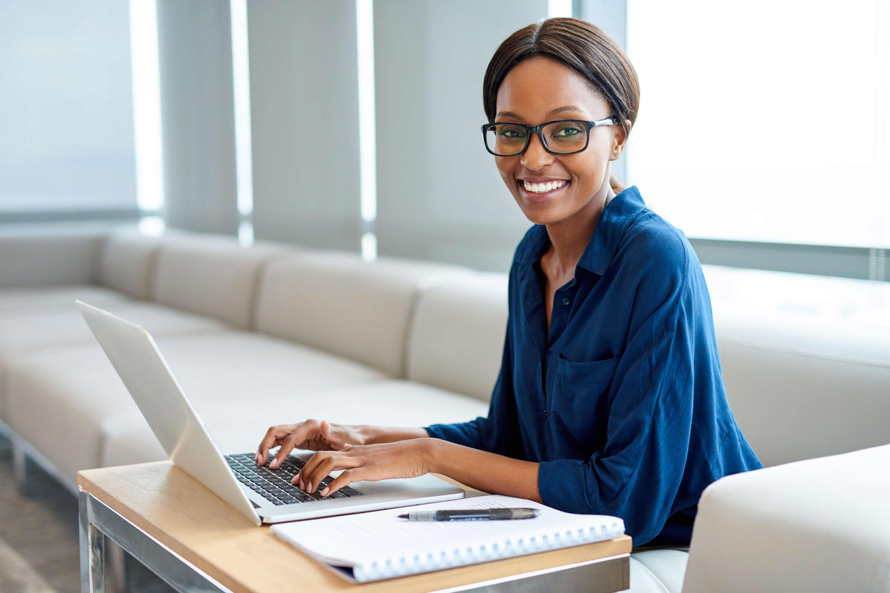 A woman sitting on a couch working on a laptop.