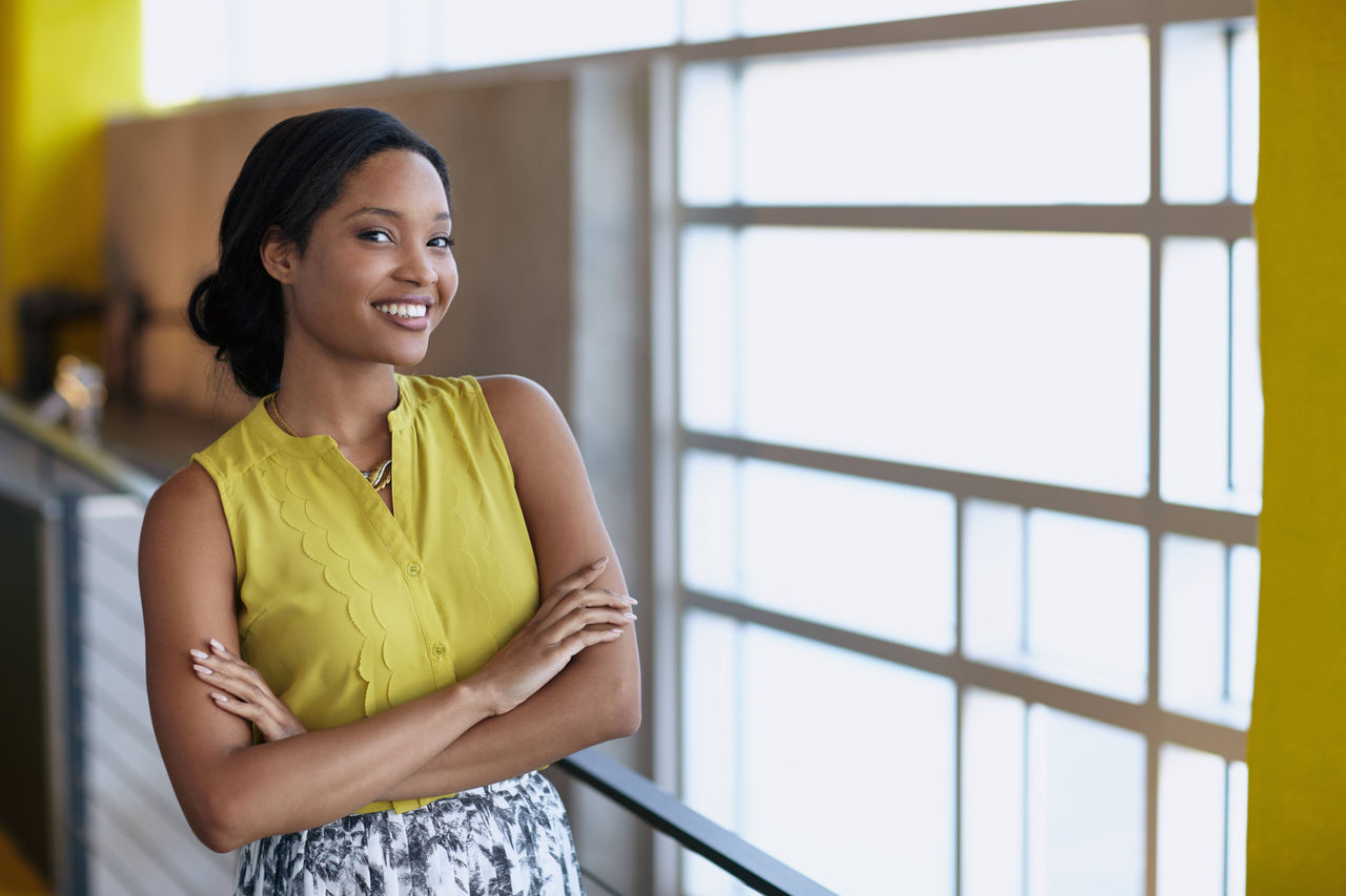A businesswoman smiling beside a window.
